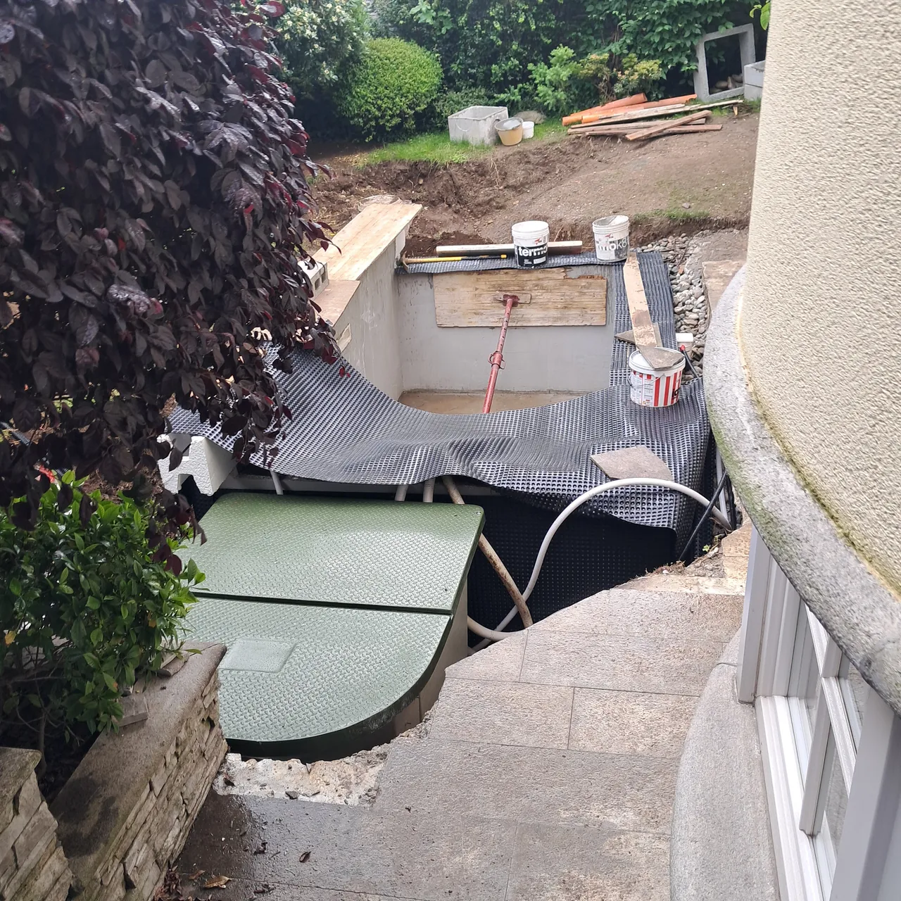Vasca accanto alla parete curva della casa e al giardino