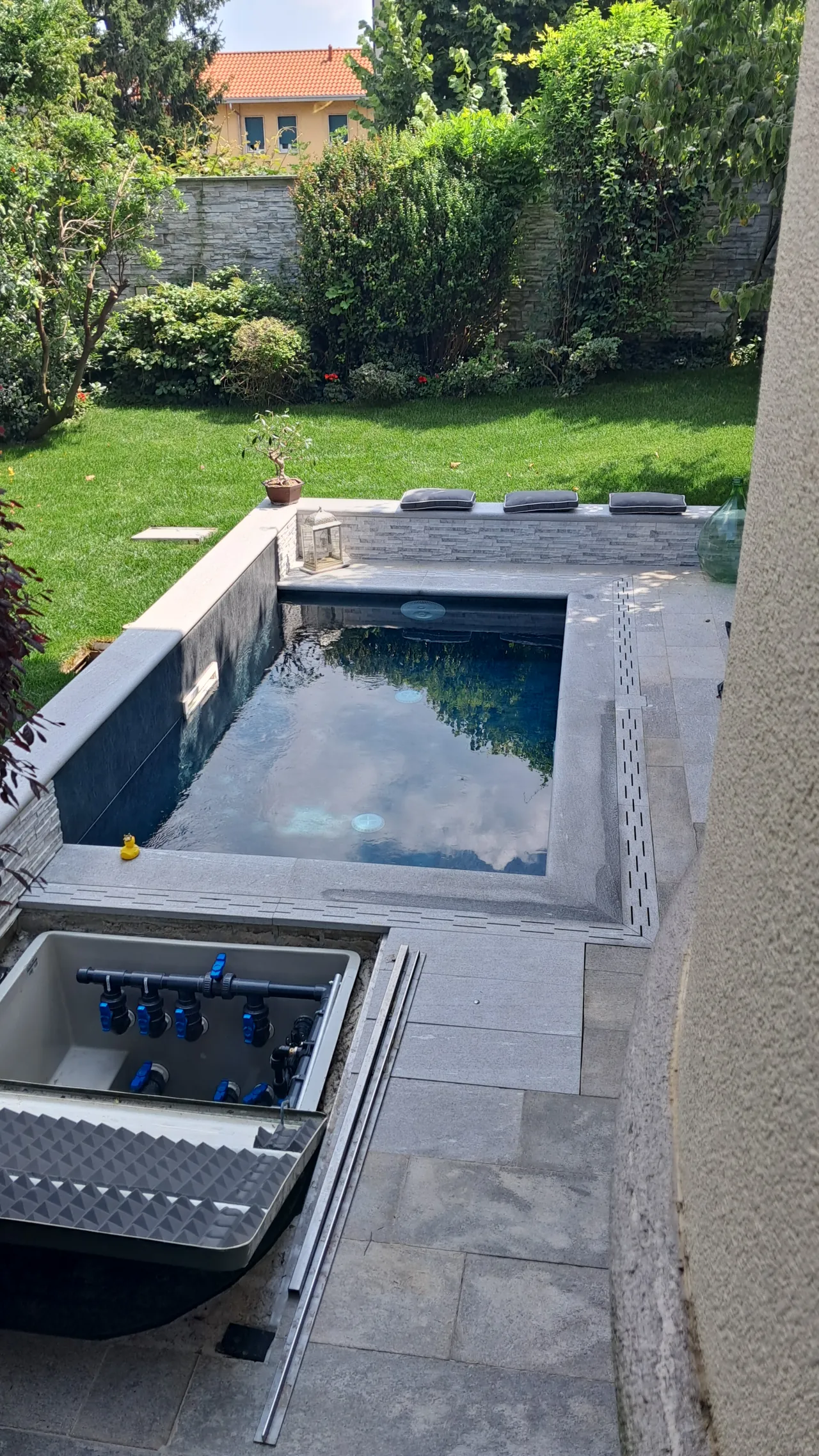 Piscina riempita d’acqua accanto alla casa e al prato